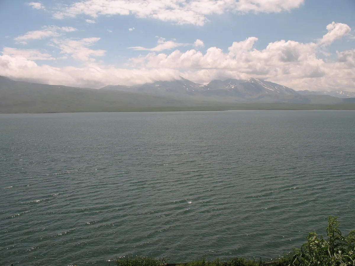 A wide mountain lake under clouded sky