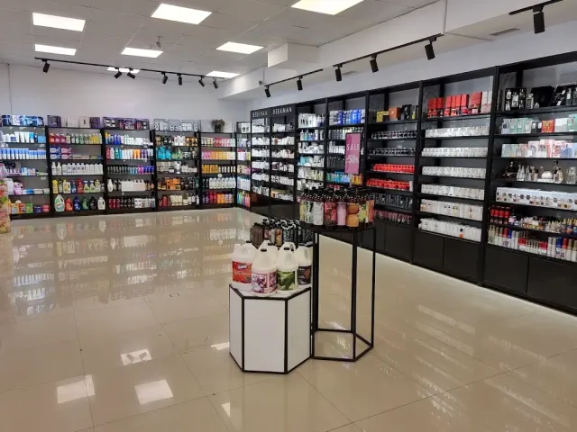 A shop with black shelves full of toiletries, a glossy floor and a display stand in the centre