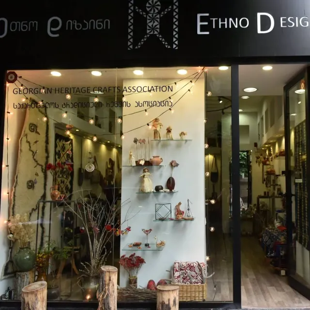 A craft shop window display with shelves of dolls and ceramics and a string of small lights