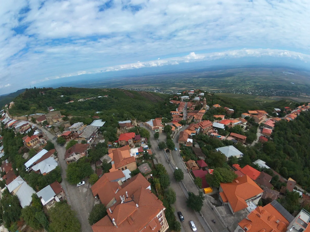 Red tiled roofs of a hillside town with a wide valley beyond, seen from above
