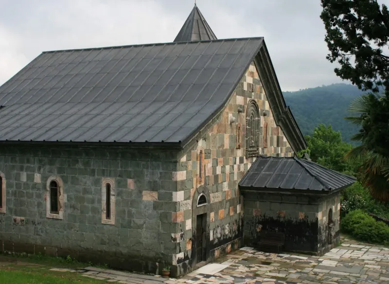 The stone church of Shemokmedi Monastery in Guria, with its steep roof and adjoining chapel against green hills