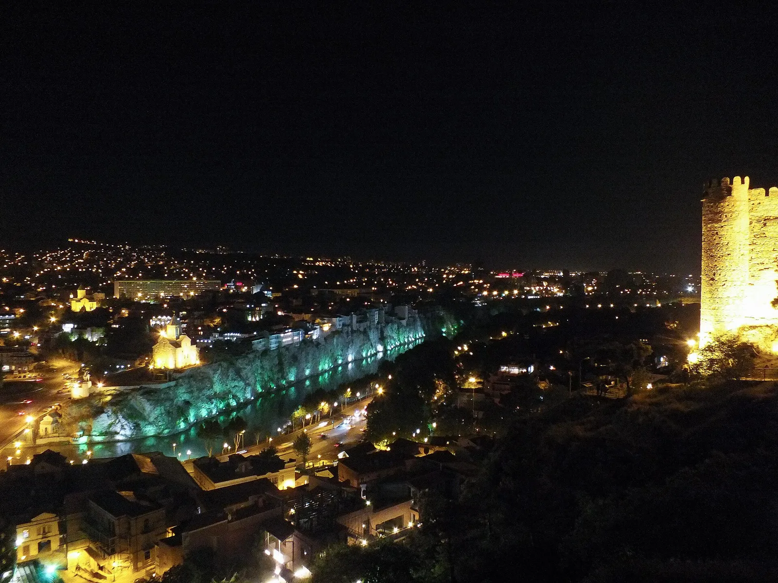 The lit city of Tbilisi at night with the illuminated bridge over the river, Georgia