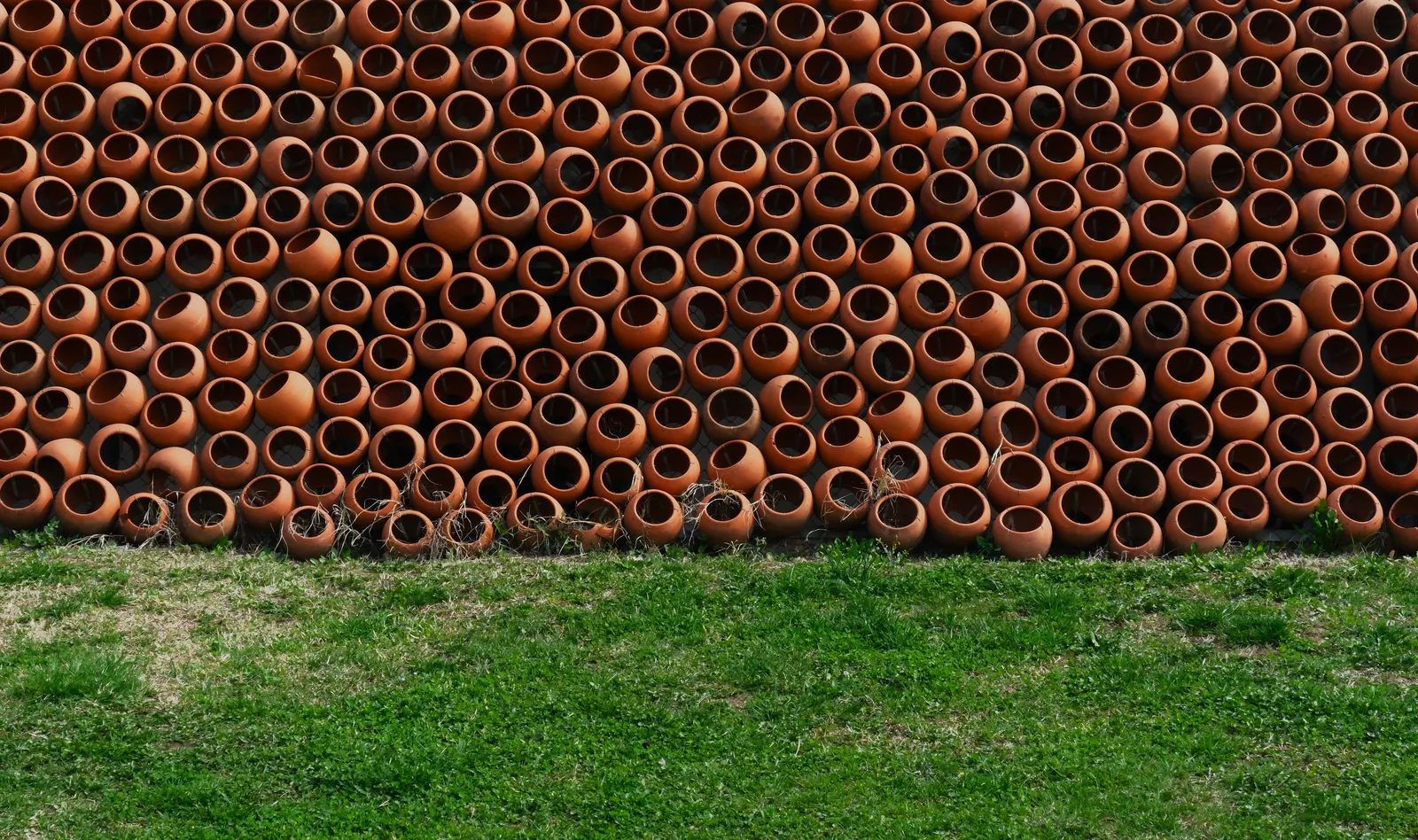 Rows of clay qvevri vessels stacked on the grass outside a Georgian winery