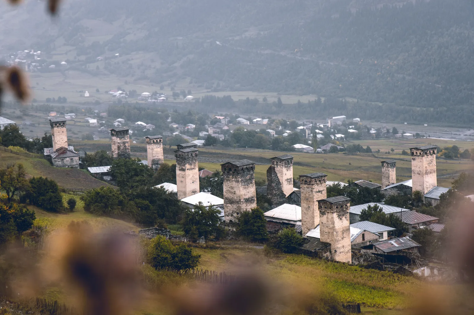 Stone defensive towers in a Svaneti village with snow peaks behind