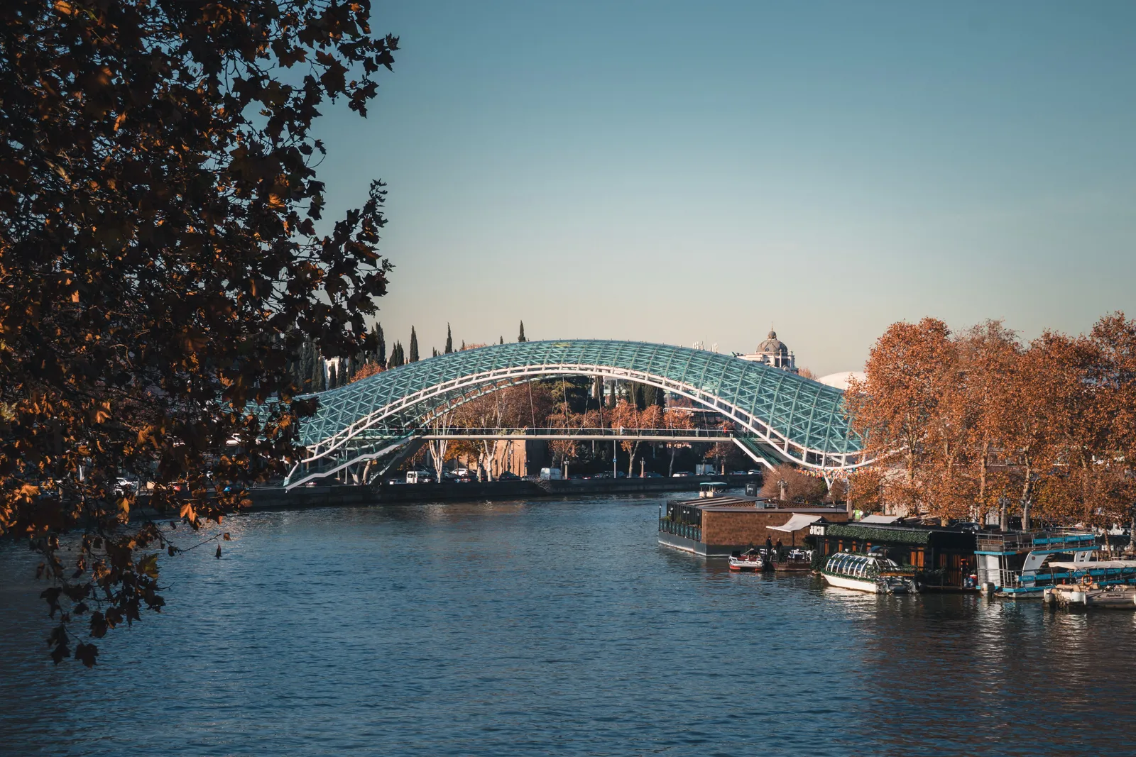 The glass Bridge of Peace over the Kura river in Tbilisi with the old town behind it