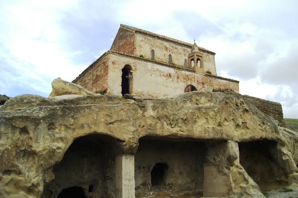 The brick church on the ridge at Uplistsikhe with the carved cave halls cut into the rock below it
