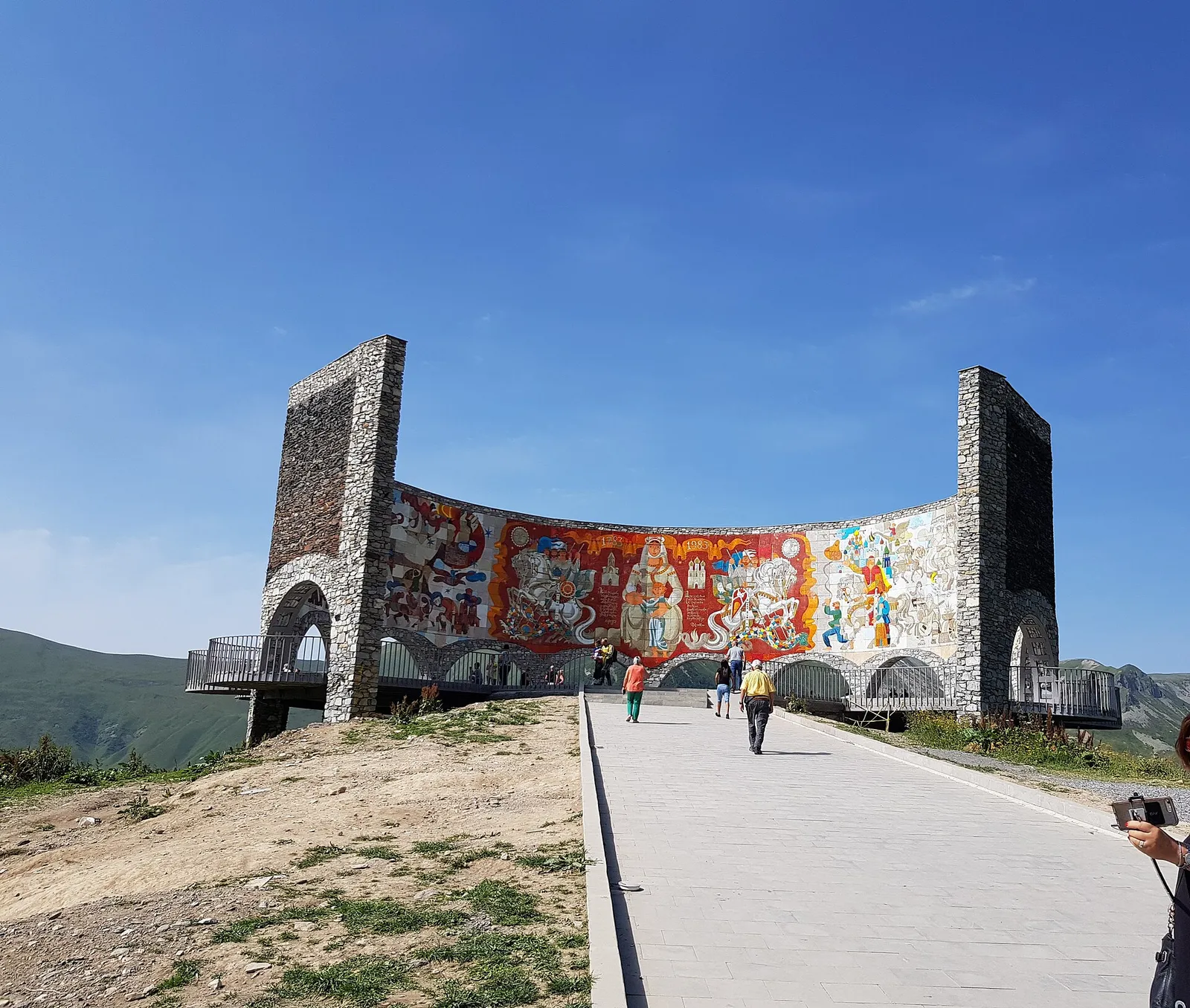 The circular Soviet era friendship monument with its mosaic wall above a valley near Gudauri, Georgia