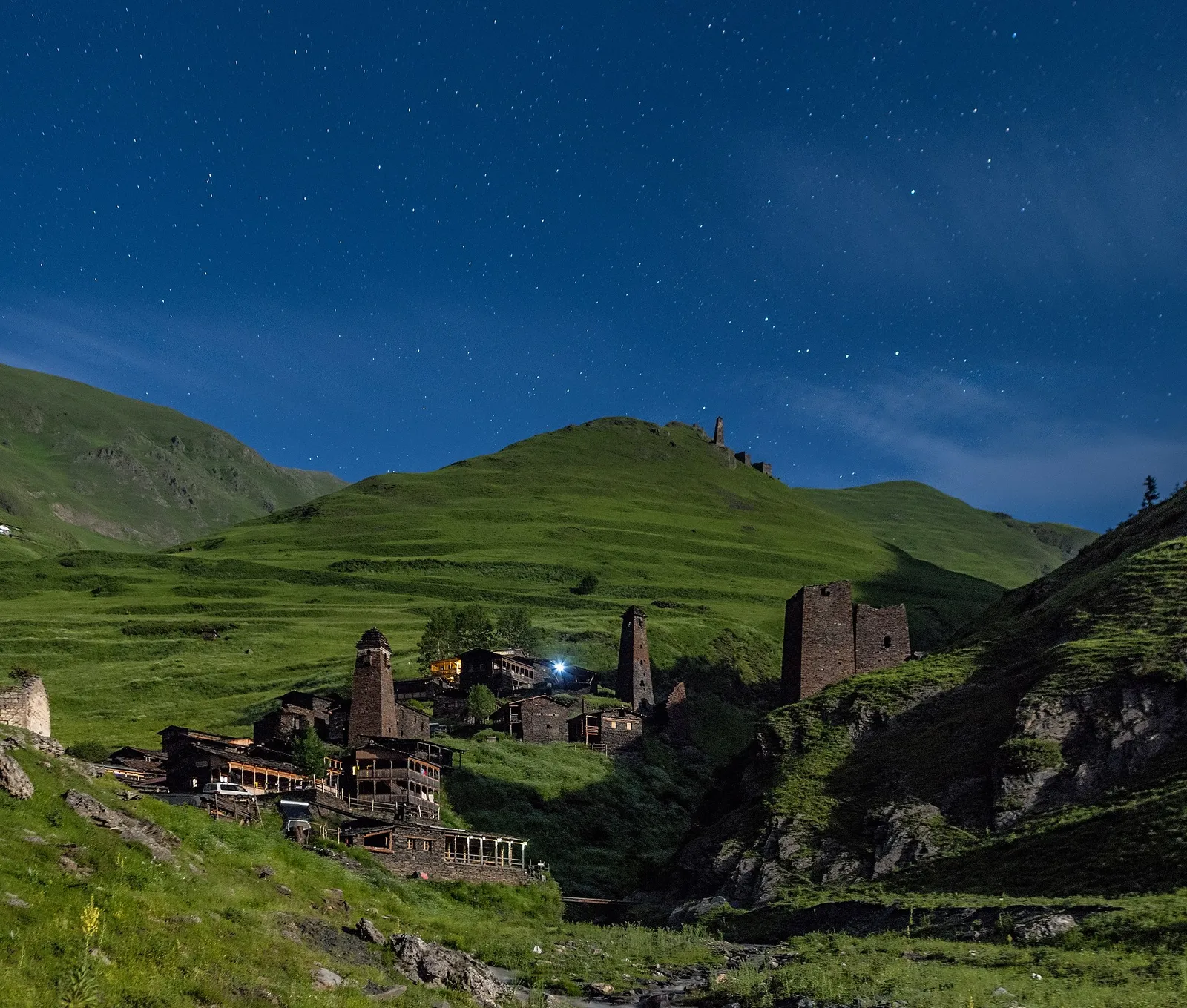 The towers and stone houses of Dartlo in Tusheti at night, with lit windows under a clear sky