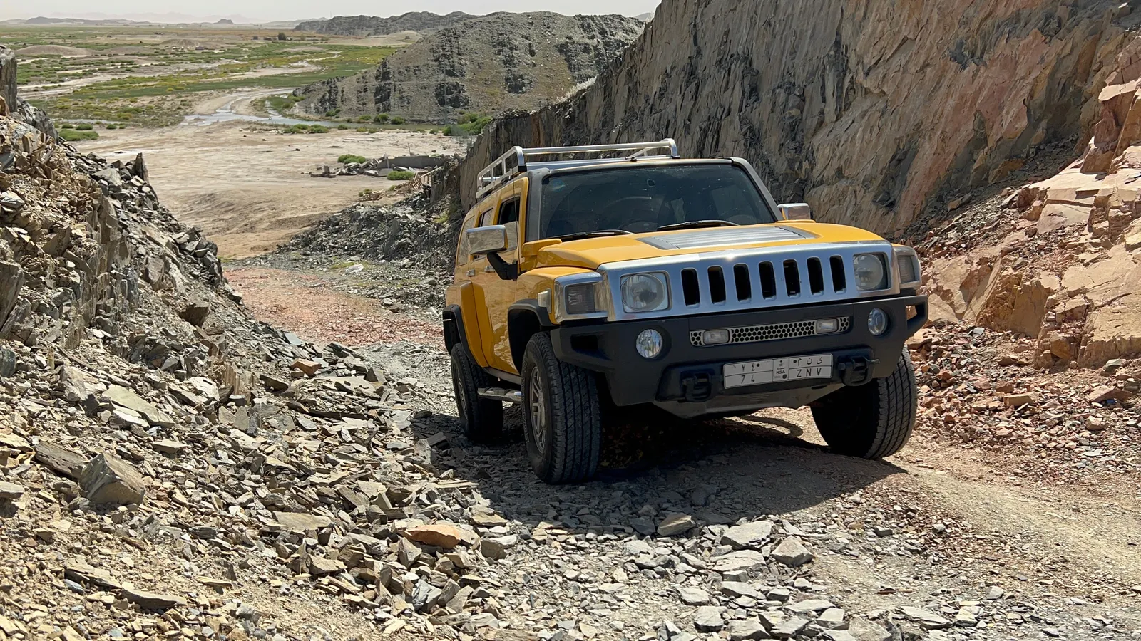 A four wheel drive on a loose gravel mountain road with bare slopes rising on either side
